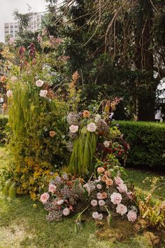 a garden filled with lots of flowers next to a lush green hedge covered in pink and white flowers