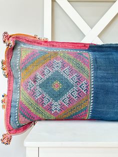 a blue and pink pillow sitting on top of a white bench