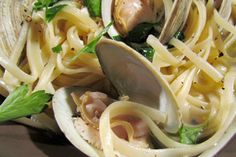 pasta with clams and greens in a white bowl