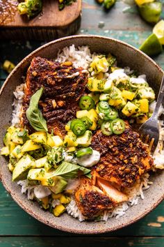 a bowl filled with rice, meat and vegetables on top of a green tablecloth