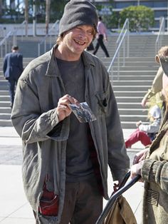 a man is talking to another man with a shopping cart in front of some stairs