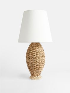 a lamp with a white shade on top of it and a rattan design base