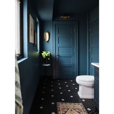 a white toilet sitting next to a blue door in a bathroom on top of a black and white floor