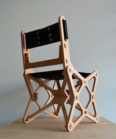 a chair made out of wooden pieces with black leather seat and back rests on a table