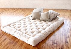 a mattress is on the floor in an empty room with hard wood floors and white walls