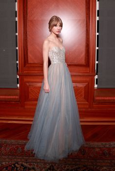 a woman standing in front of a wooden wall wearing a dress with sequins on it