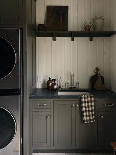 a washer and dryer in a small room with wood paneling on the walls