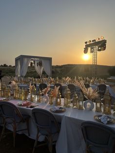 an outdoor dinner setup with candles and place settings for guests to sit at the table