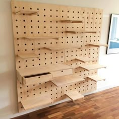 a wooden shelf with holes on it in front of a wall mounted pegboard board