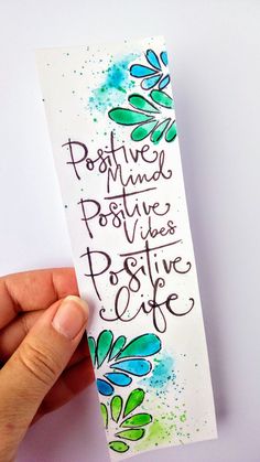 a hand holding up a bookmark with the words positive minds and positive life written on it