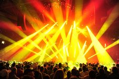 a large group of people at a concert in front of bright colored lights on the stage