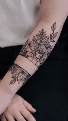 a woman's arm with flowers and leaves on it