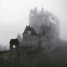 an old castle is surrounded by fog in black and white