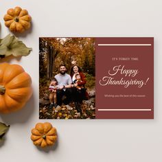 a happy thanksgiving card with an image of a family sitting on the ground surrounded by fall leaves and pumpkins