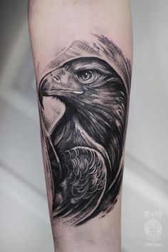 an eagle tattoo on the leg with black and grey ink, it looks like he is holding