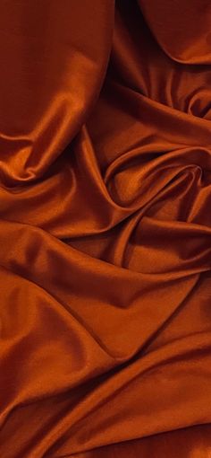 an orange sheet is laying on top of a bed with brown sheets and pillow cases