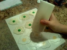 a person holding a cup in front of some cookies on a paper towel with green buttons