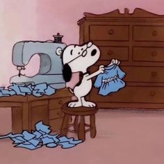 a cartoon dog standing in front of a sewing machine with clothes on the table next to it