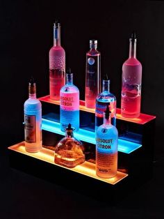 several bottles are lit up in the dark with red light on them and one bottle is empty