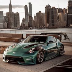 a green sports car parked in front of a city skyline