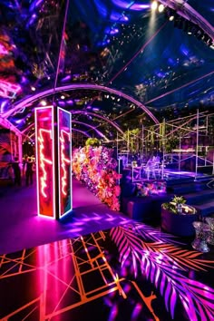 an indoor event venue with purple lighting and floral arrangements on the walls, decorated in neon colors