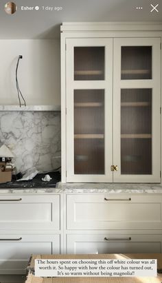 a kitchen with white cabinets and marble counter tops