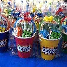 lego buckets filled with candy and candies on a blue tablecloth covered table