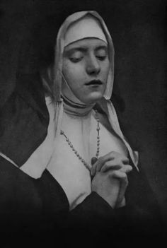 a black and white photo of a nun holding a rosary