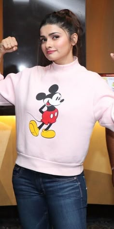 a woman in a pink mickey mouse sweater flexing her muscles