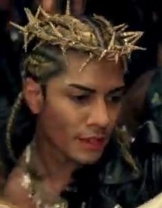 a young man wearing a crown of gold stars on his head and looking at a cell phone