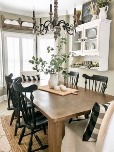 a dining room table with black chairs and a white vase filled with flowers on it