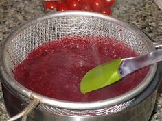 a metal pot filled with red liquid next to tomatoes