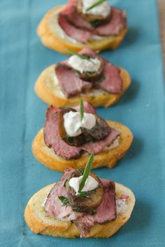 small appetizers with meat and cream cheese on them are lined up on a blue table cloth