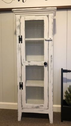 an old white cabinet with glass doors and metal handles is displayed in front of a wall