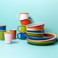 a stack of colorful cups and plates on a blue background with one cup in the middle