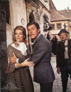 a man and woman standing in front of a building on a cobblestone street