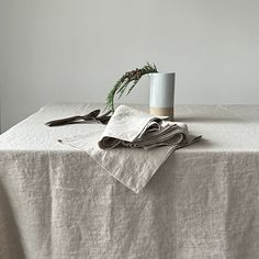 a white table topped with a cup and napkin