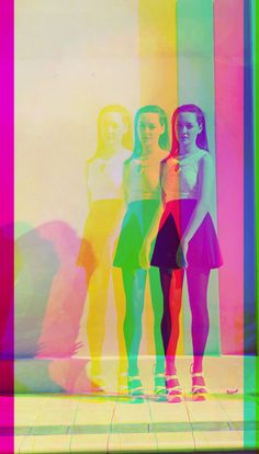 three girls standing in front of a multicolored wall