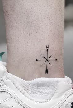 a small black and white compass tattoo on the side of a person's leg