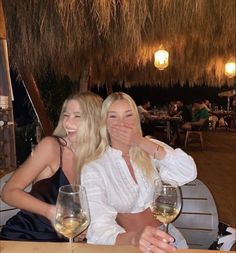 two women sitting at a table with wine glasses