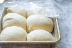 several uncooked bread rolls in a metal pan