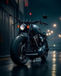 a black motorcycle parked in front of a building on a wet street at night time