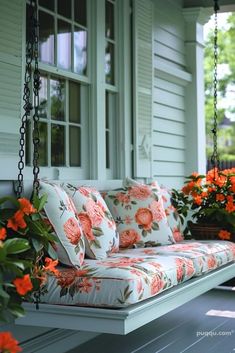 a porch swing with pillows and flowers on it