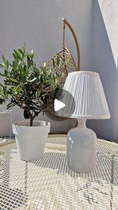 a table with two white vases and a lamp on it next to a potted plant