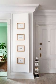 an empty room with white walls and wood flooring, framed pictures on the wall