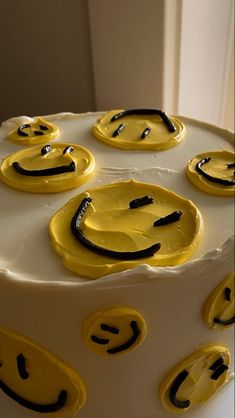 a white cake with yellow icing decorated with smiley faces