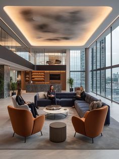 two people sitting on couches in a large room with high ceilings and floor to ceiling windows