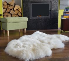 a white sheepskin rug on the floor in front of a fire place and chair