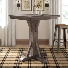 a wooden table with two stools in front of it and pictures on the wall