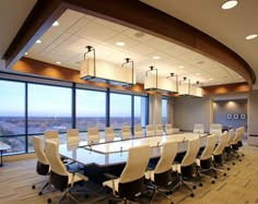 an empty conference room with large windows overlooking the cityscape, and white chairs